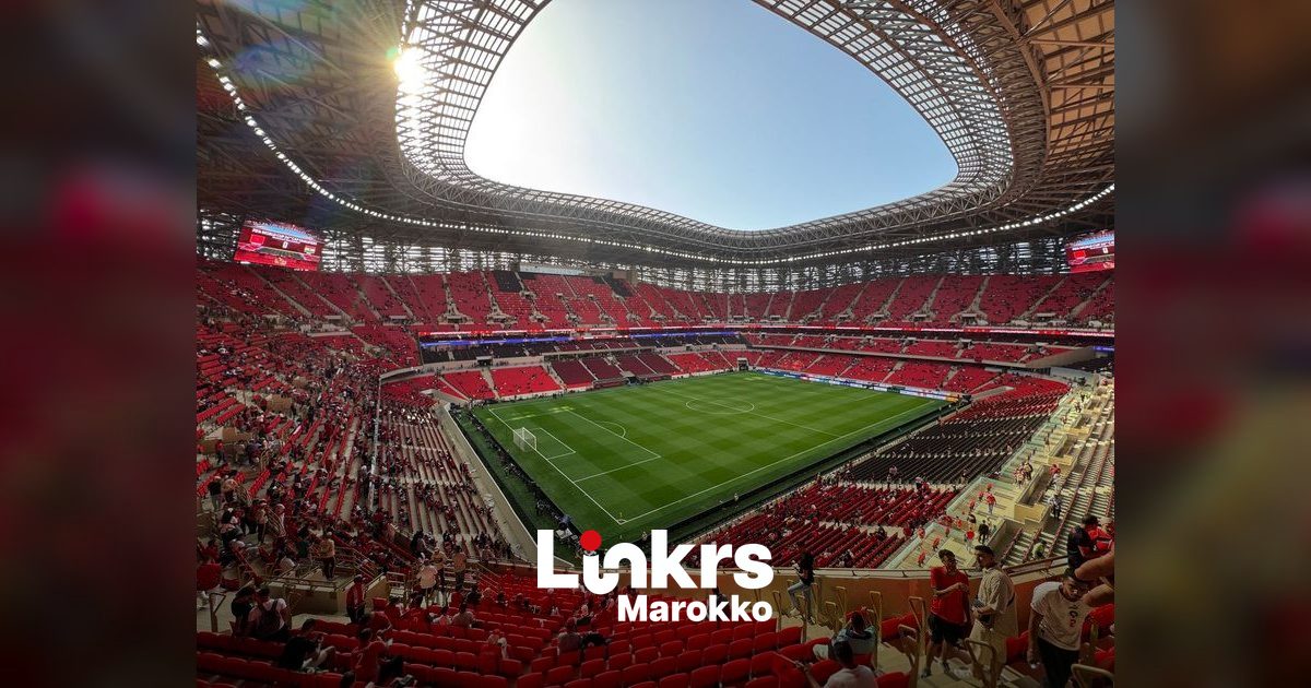 Groot voetbalstadion met vollopende tribunes tijdens een wedstrijd