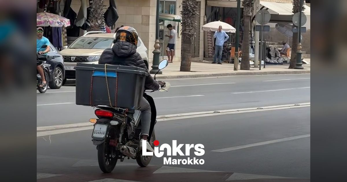 Maaltijdbezorger op een scooter in het drukke stadsverkeer