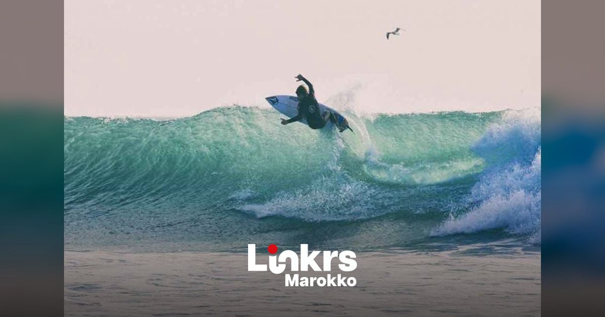 Vrouwelijke surfster loopt met haar surfplank het strand op aan de Marokkaanse kust